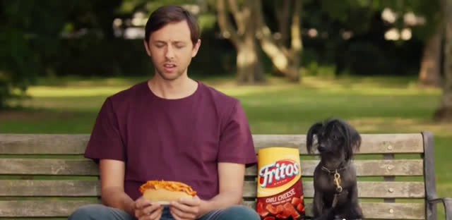  Man eating a hot dog in the park with his dog